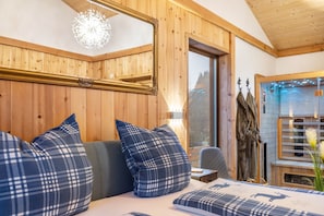 A wooden interior with a bed, pillows, a mirror, and a window. - Holiday Home 'Vogelsberger Zirbenstüberl' with Mountain View, Wi-Fi & Air Conditioning (Grebenhain)