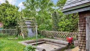 Un jardin avec un parterre surélevé, une clôture en bois et un abri de jardin.