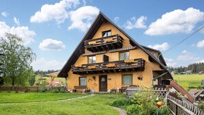 Un chalet traditionnel doté d’un balcon en bois, d’un porche et d’un jardin bien entretenu.