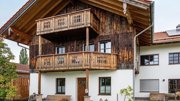 A two-story wooden building with a balcony, windows, and a door.