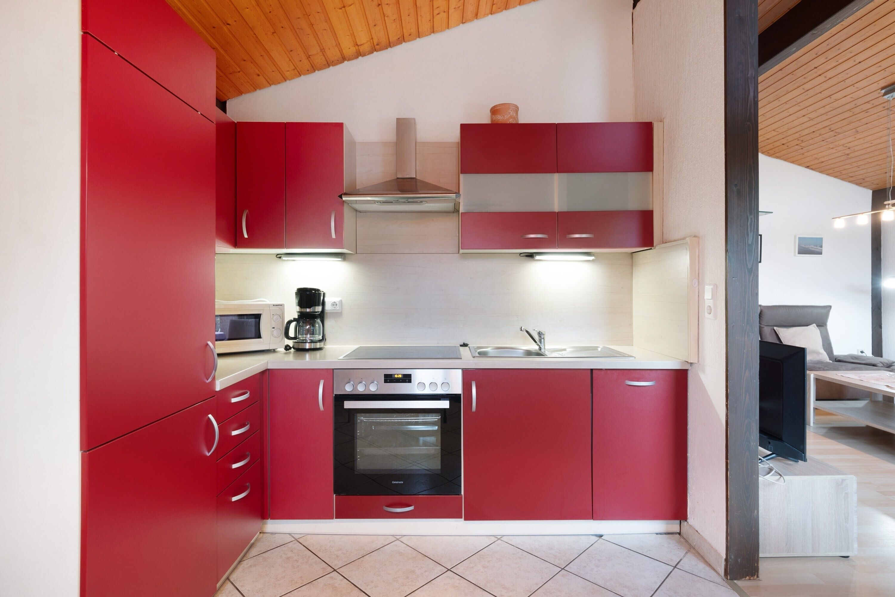 A kitchen with red cabinets, a built-in oven, and a microwave.