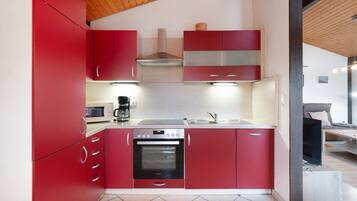 A kitchen with red cabinets, a built-in oven, and a microwave.