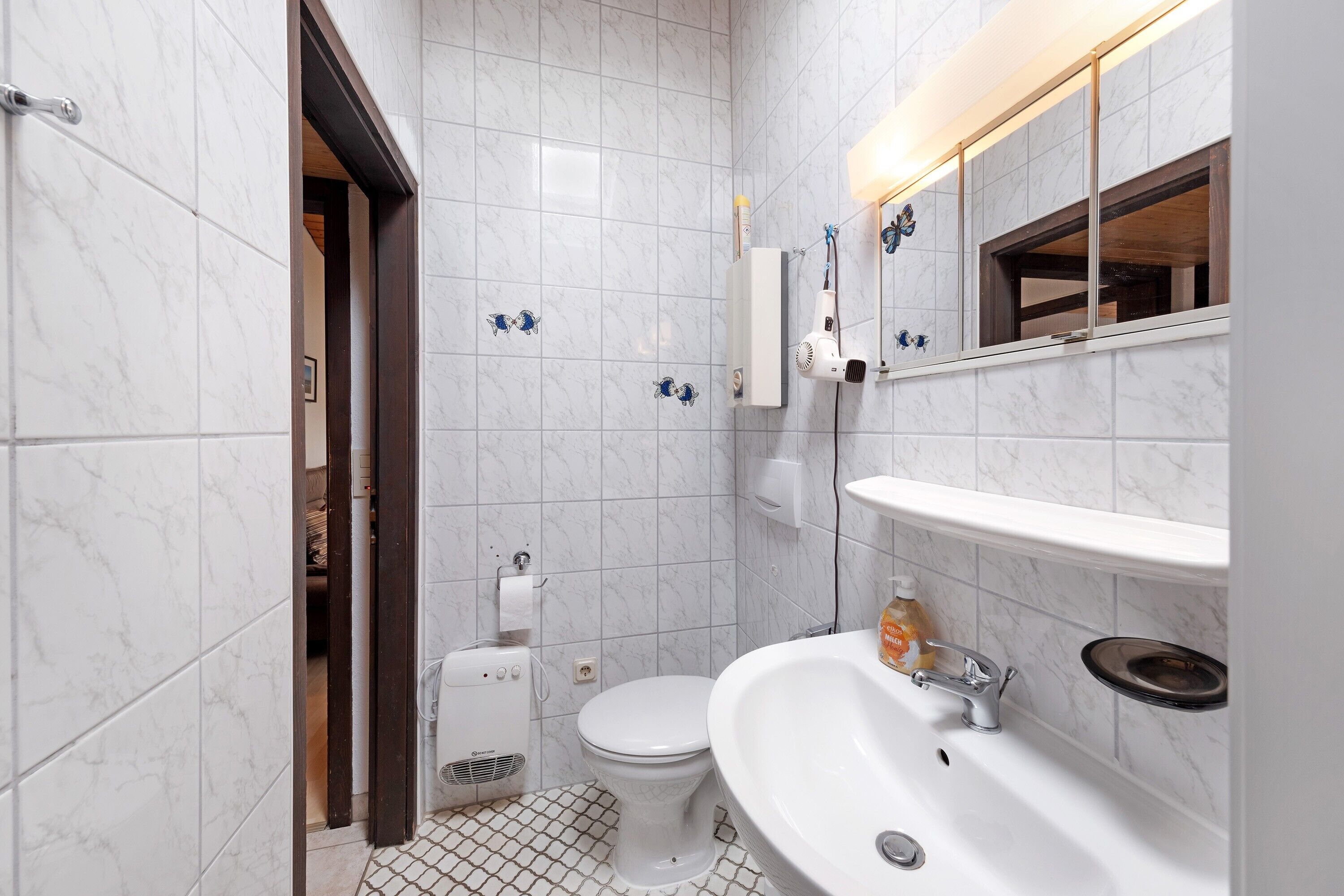 Een badkamer met toilet, wastafel en spiegel.