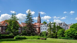 Un bâtiment historique doté d’une tour imposante, entouré d’une végétation luxuriante et d’autres exemples d’architecture traditionnelle.