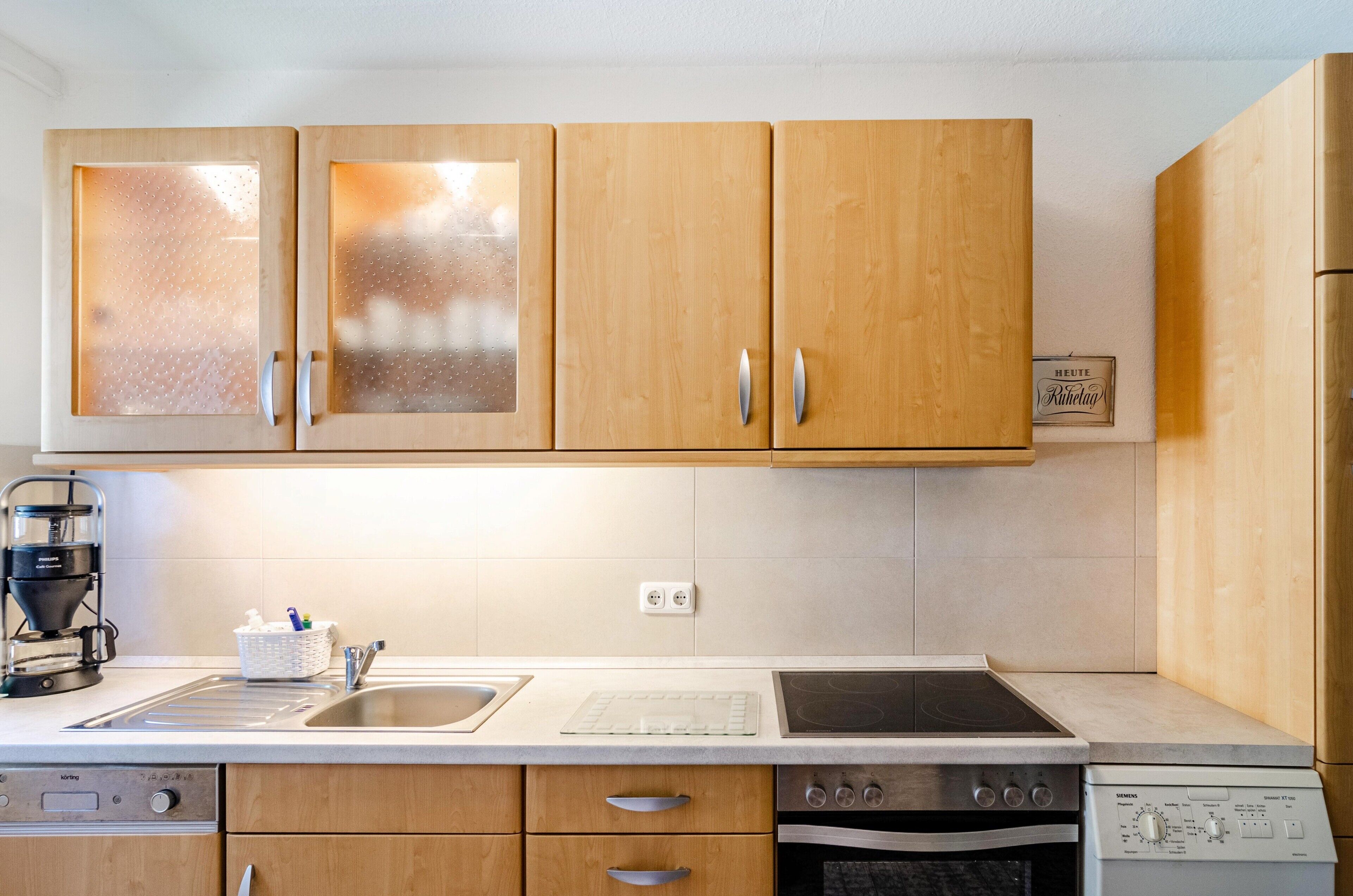 A kitchen with wooden cabinets, a stainless steel sink, a coffee maker, and a built-in oven.