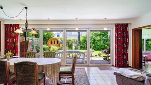 Un coin repas avec une table ronde, des chaises et une vue sur le jardin grâce à de grandes portes coulissantes.