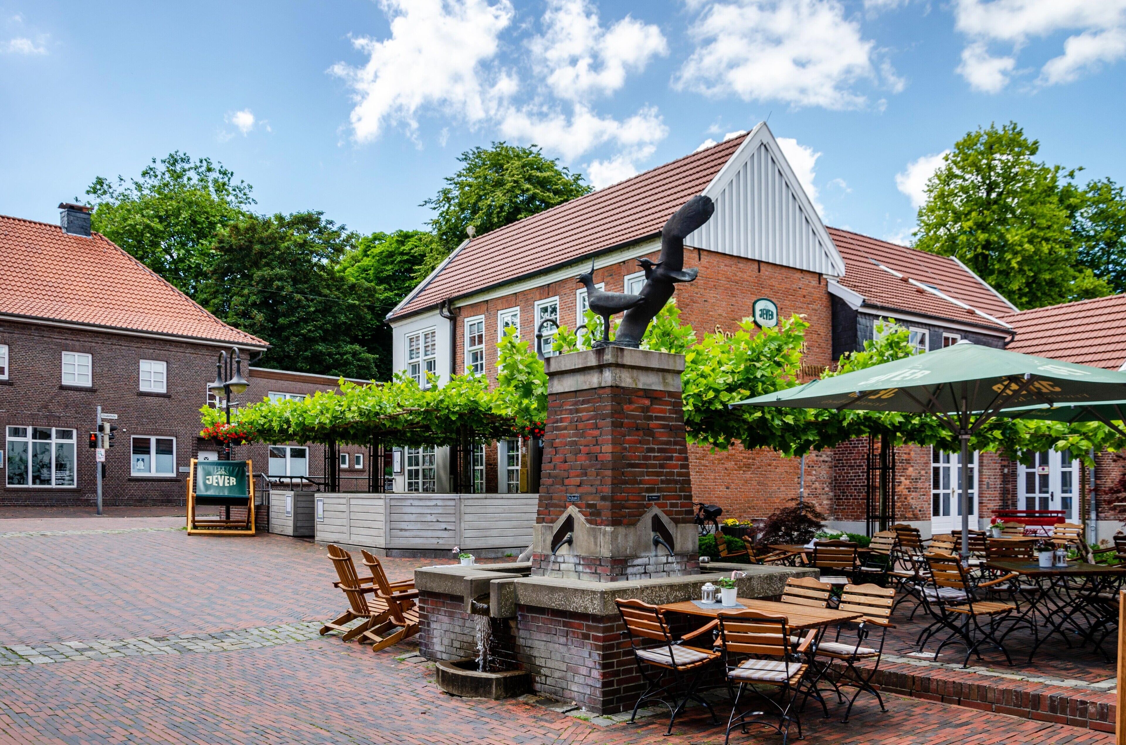 A courtyard with outdoor seating, a brick building, and a statue.