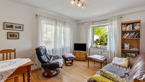 Una sala de estar con un sofá de cuero, una mesa de madera, un sillón de cuero, un televisor y una estantería.