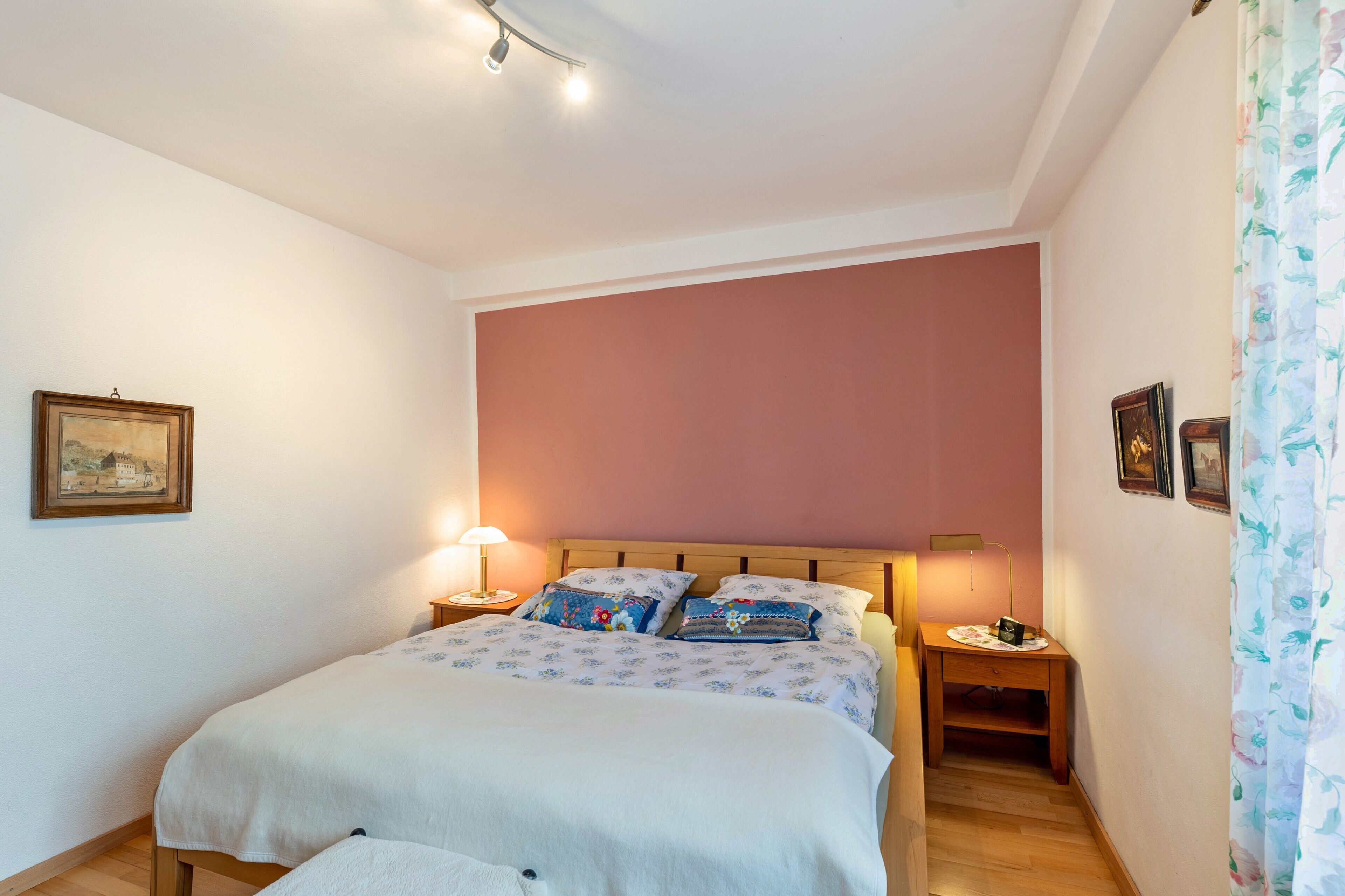 Una camera da letto con un letto, due comodini, un tavolino, una lampada e un quadro appeso al muro.