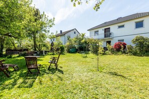 Ett bostadsområde med en gräsyta, trädgårdsmöbler och en vit byggnad med en balkong.