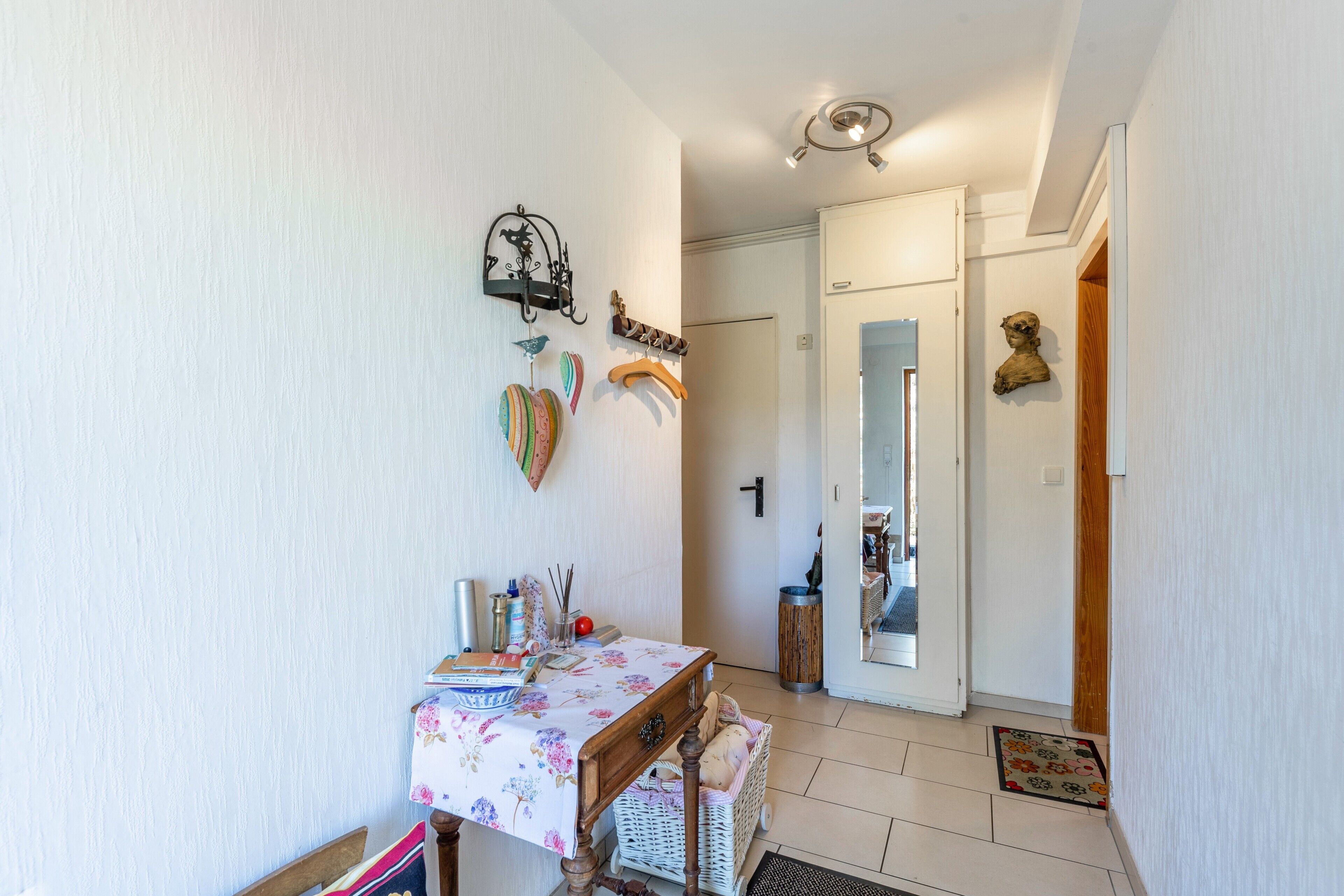Un pasillo con una mesa, una cesta y una puerta que da a otra habitación.