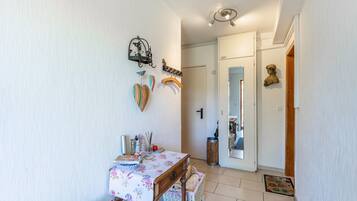 Un pasillo con una mesa, una cesta y una puerta que da a otra habitación.