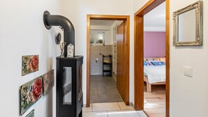 Un pasillo que conduce a un dormitorio con una cama, una puerta de madera y un espejo en la pared.