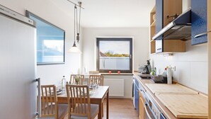 Une cuisine moderne avec une table à manger, des chaises, une fenêtre et une vue sur l’extérieur.