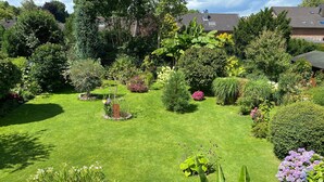 Un jardin bien entretenu, agrémenté de diverses plantes et doté d’une pelouse centrale.
