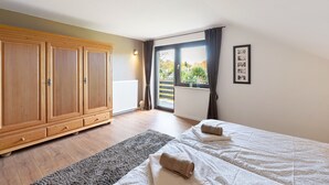Une chambre dotée d’une grande armoire, d’un lit avec des serviettes, d’une fenêtre avec des rideaux et d’un radiateur.