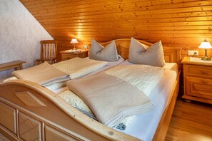 Ein Schlafzimmer mit Holzwänden, einem Bett, zwei Nachttischen, einem Sessel und einer Lampe.