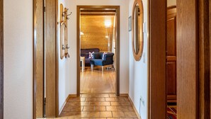 Un pasillo con puertas de madera, techo de madera y un sofá al fondo.