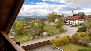 A view from a window overlooking a town with a church, a winding road, and a small stream. - Apartment 'Ferienwohnung Abendrot' with Mountain View, Shared Garden and Wi-Fi (Breitnau)