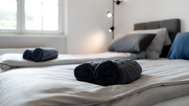Ett hotellrum med två sängar, ett nattduksbord, en lampa och ett fönster.