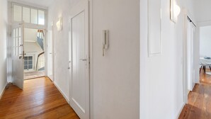 En hall med trägolv, vita väggar och dörrar som leder till andra rum.