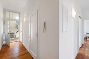 Käytävä, jossa on puulattia, valkoiset seinät ja ovet, jotka johtavat muihin huoneisiin.