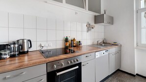 Ett modernt kök med en bänkskiva i trä, vitvaror i rostfritt stål och vita köksluckor.