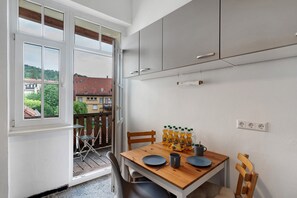 A kitchen with a wooden table, grey cabinets, and a view of the outside.