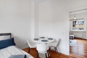 A bedroom with a bed, a bedside table, and a small round table with chairs.