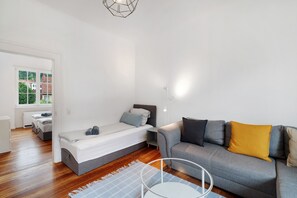 A modern, well-lit room with a bed, sofa, and a view of a brick building through a window.
