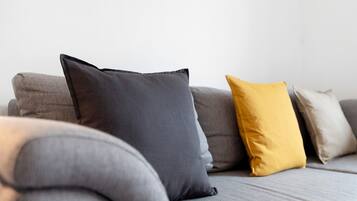 A grey sofa with three cushions in different colors.