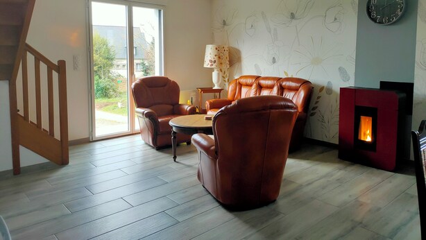 Un salon avec une cheminée, des fauteuils en cuir, une table et une horloge au mur.