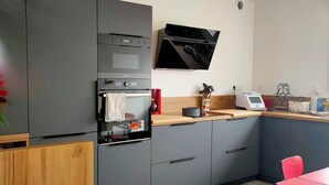 Une cuisine moderne avec des meubles gris, un four encastré, un four à micro-ondes et une machine à café.