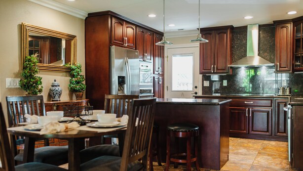 Una cocina moderna con gabinetes de madera oscura, electrodomésticos de acero inoxidable y una isla central.