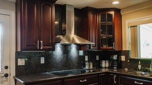 Una cocina con gabinetes de madera oscura, una campana extractora de acero inoxidable, una encimera de granito y un lavavajillas integrado.
