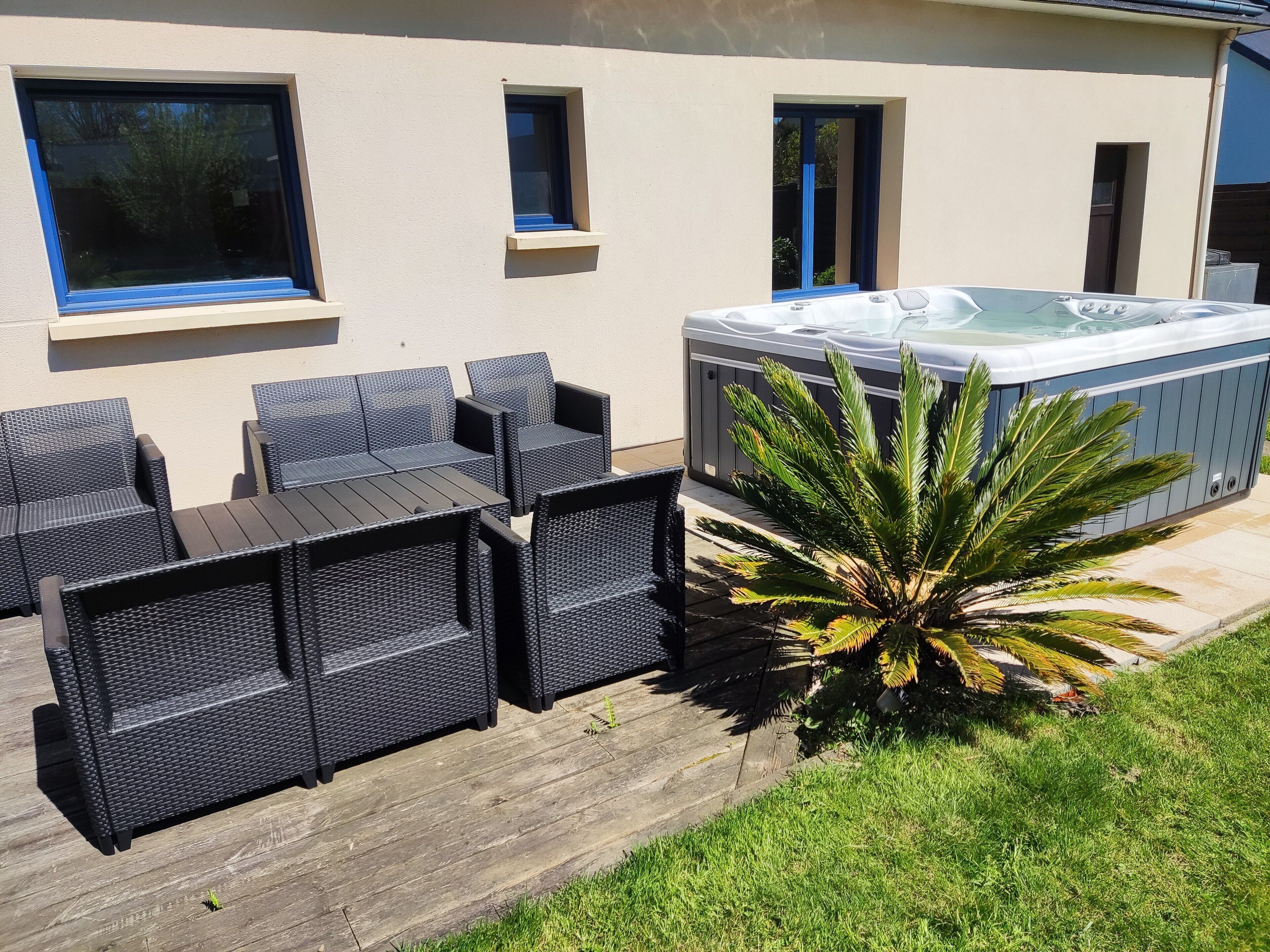 An outdoor seating area with wicker furniture and a hot tub.