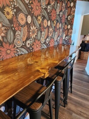 A long wooden dining table with a unique design, surrounded by black metal chairs.