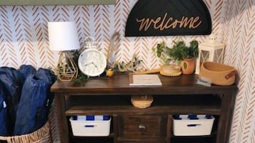A room with a desk, a welcome sign, a clock, a lamp, and storage drawers.