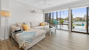 Un salon spacieux doté d’une grande fenêtre, d’un ventilateur de plafond et offrant une vue sur une étendue d’eau.