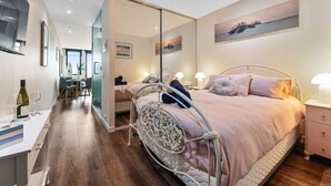 Een slaapkamer met een bed, nachtkastje en een spiegel.