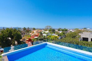 Una piscina azul cristalina con vista a una zona residencial y montañas al fondo.