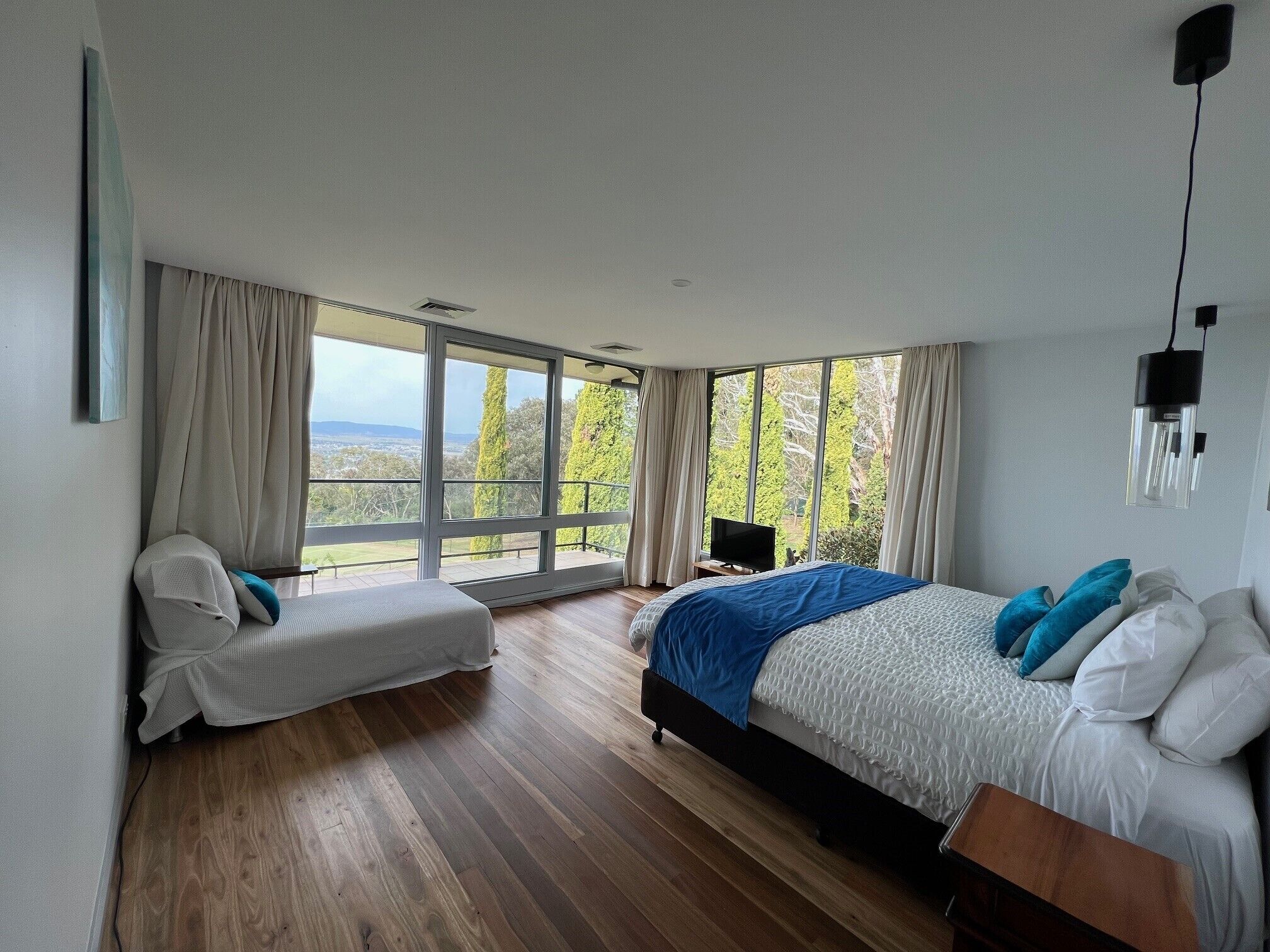 Una camera da letto con un'ampia finestra, un letto, un comodino e una sedia.