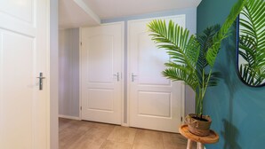 Ein Flur mit zwei weißen Türen, einem Blumentopf auf einem Holzschemel und einer wandartigen Farbe in Türkis.