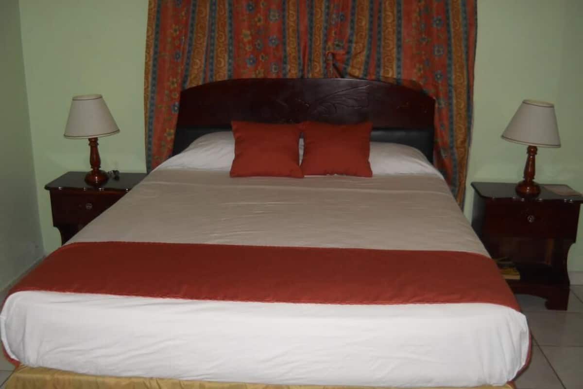 A bed with a wooden headboard, two nightstands with lamps, and a patterned curtain.