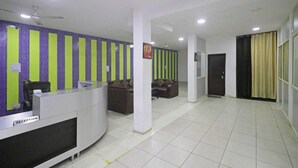 A reception area with a reception desk, a sofa, and a wall with vertical stripes. - Airport Hotel Ashoka Palace (New Delhi)