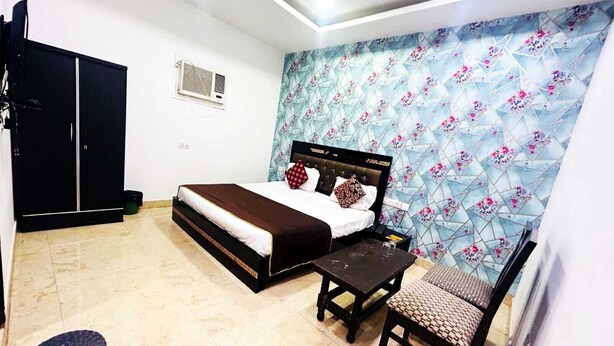 A bedroom with a bed, a desk, a chair, a wardrobe, and a decorative wall. - Airport Hotel Ashoka Palace (New Delhi)