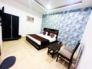 A bedroom with a bed, a desk, a chair, a wardrobe, and a decorative wall. - Airport Hotel Ashoka Palace (New Delhi)