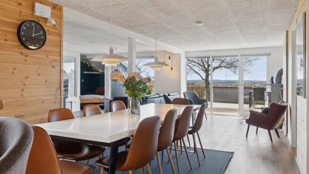 Un espace repas moderne avec une grande table, des chaises et des luminaires suspendus.