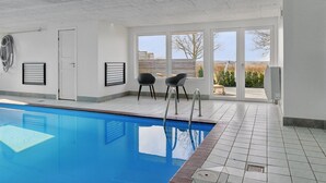 Une piscine donnant sur l’extérieur, une porte et deux chaises.