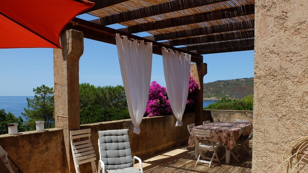 A covered patio with a table and chairs, overlooking a scenic view of the sea and hills. - Loue Maison de Famille Dans le Golf de Lava à Proximité de la mer (Villanova)